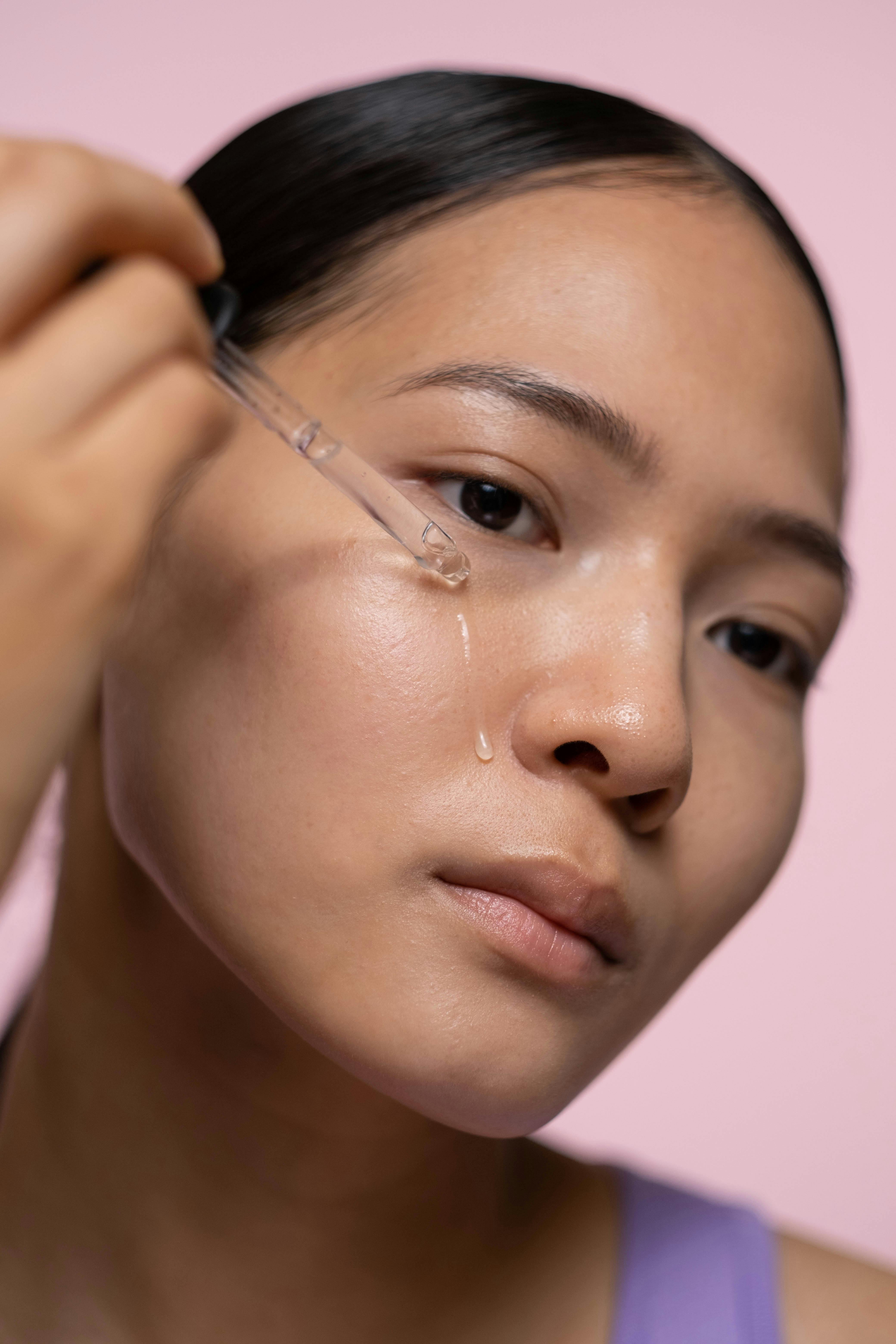 Woman massaging botanical face oil into skin as part of a minimalist skincare routine