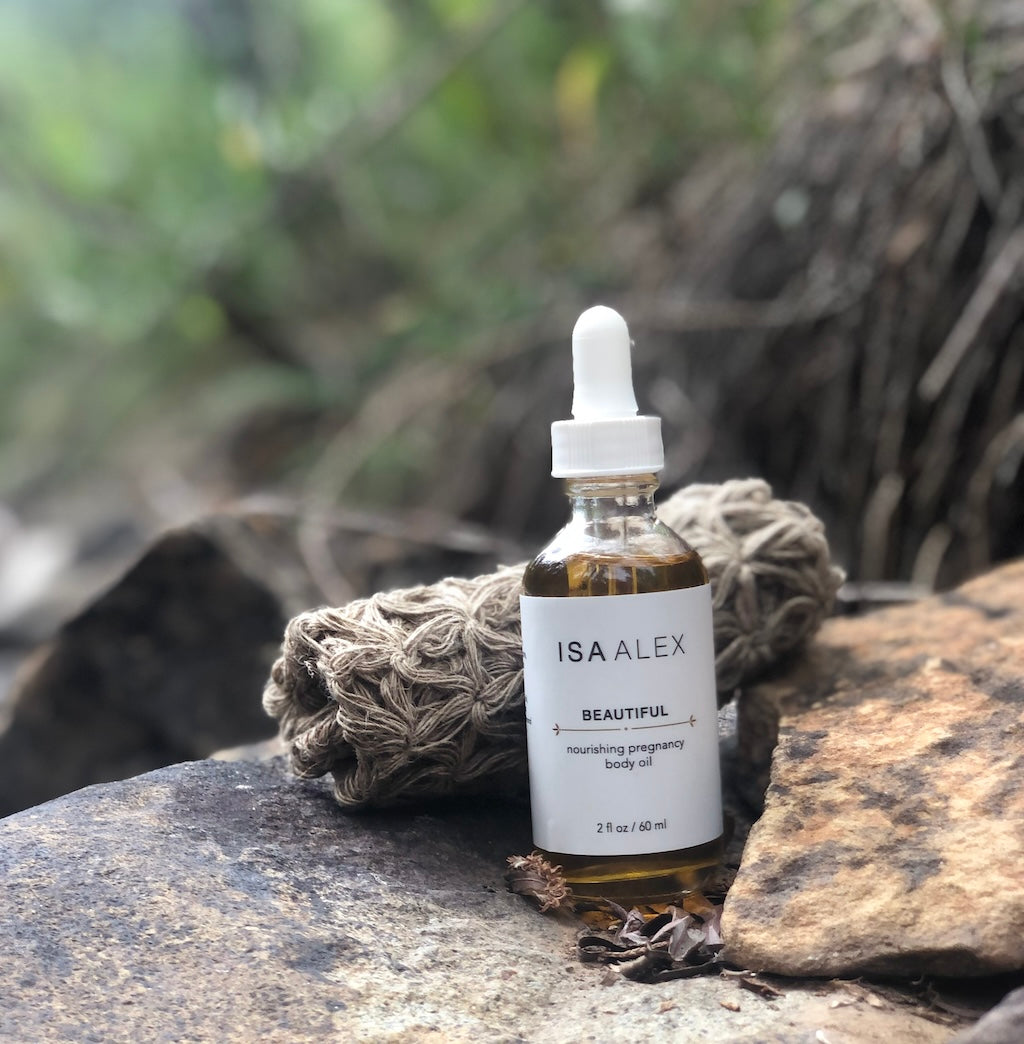 Bottle of ISA ALEX body oil on a rock with natural background